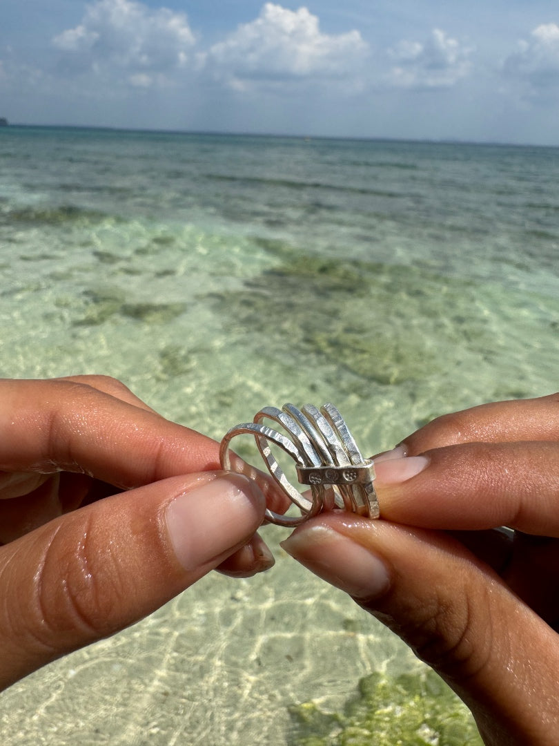 Silver ring held by hands with a clear water and blue sky background