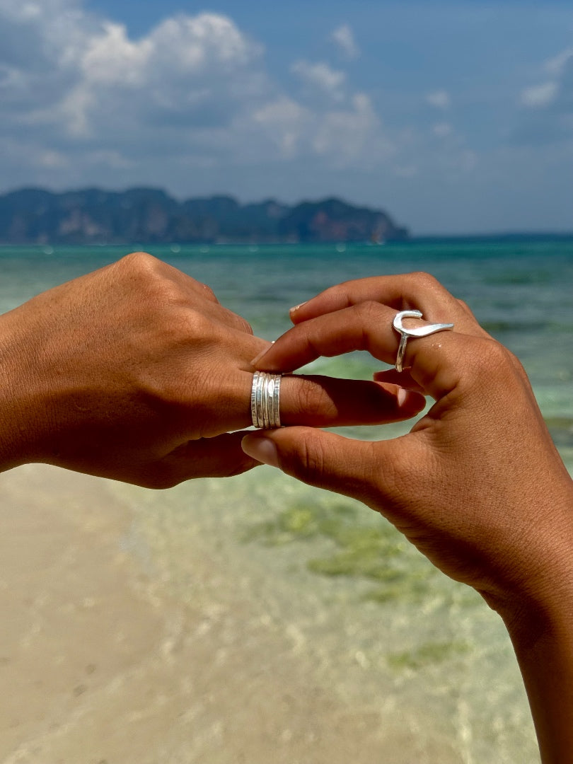 Two hands holding each other with rings on a beach