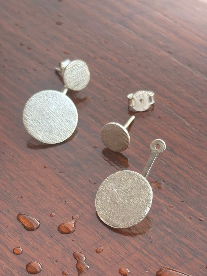 Silver round earrings on a wooden surface