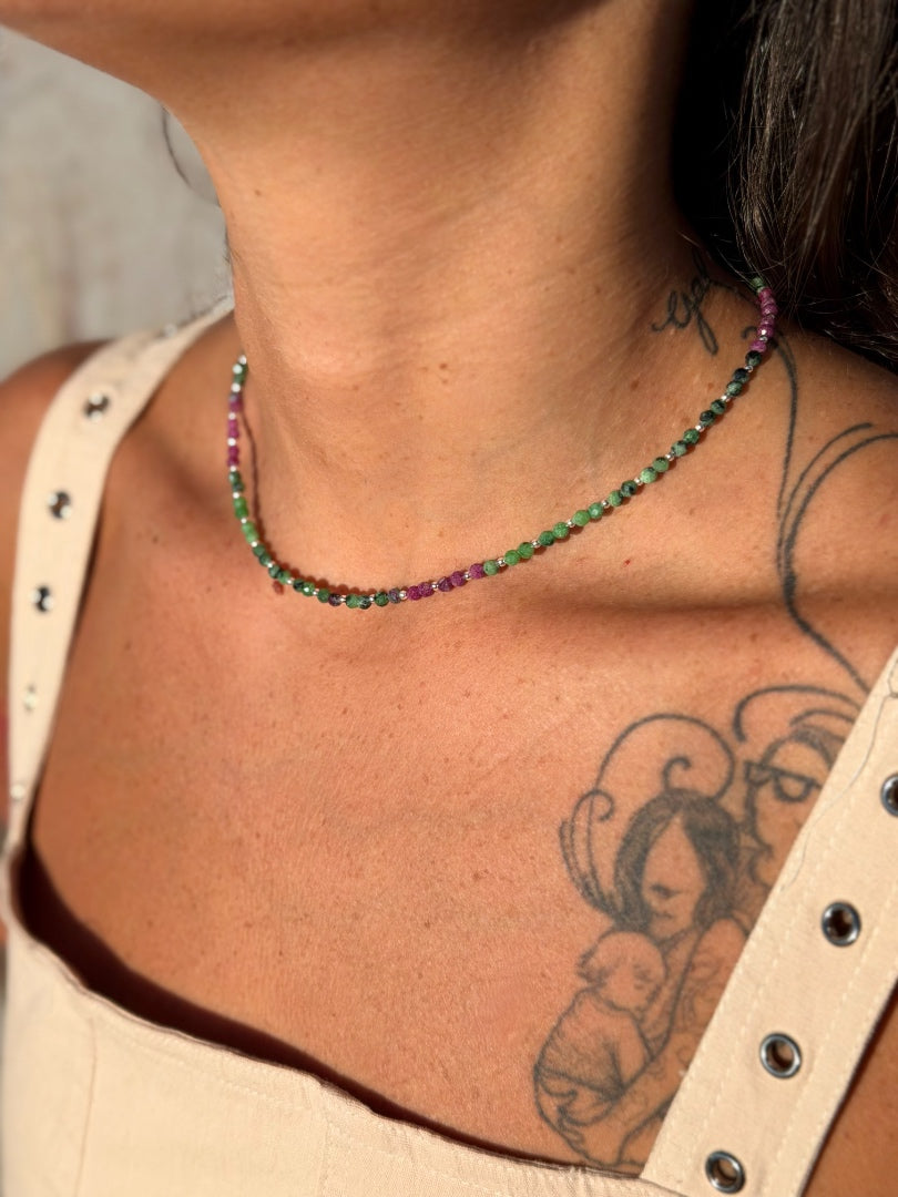 Necklace with multicolored beads worn by a person with tattoos on their neck and shoulder.