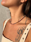 Close-up of a person wearing a beaded necklace with a neutral background