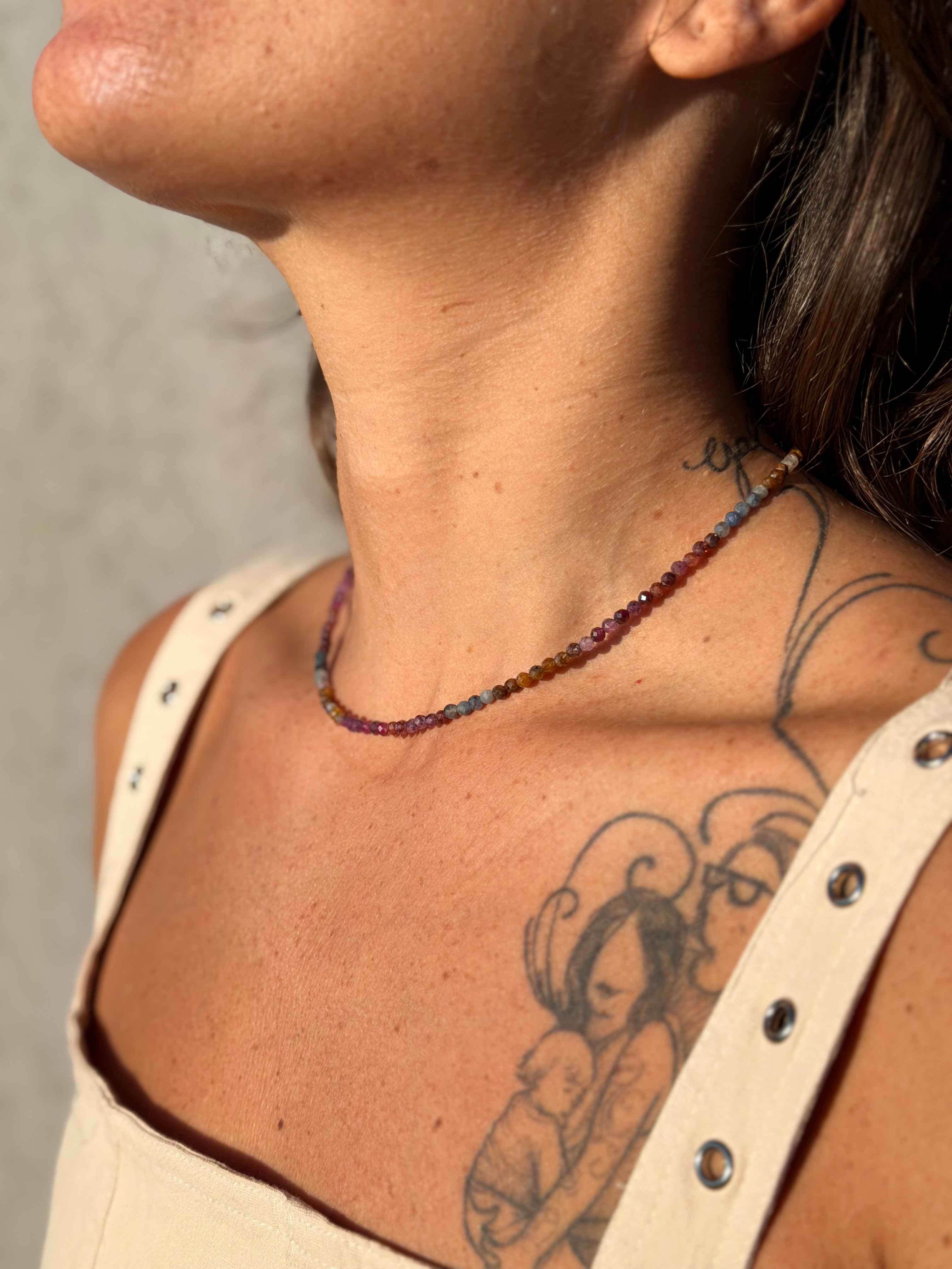 Close-up of a person wearing a beaded necklace with a neutral background