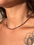 Close-up of a person wearing a multicolored beaded necklace with visible tattoos on the neck and shoulder.