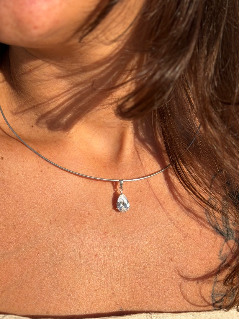 Close-up of a necklace with a teardrop-shaped pendant on a person's neck.
