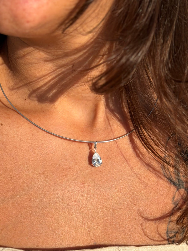 Close-up of a necklace with a teardrop-shaped pendant on a person's neck.