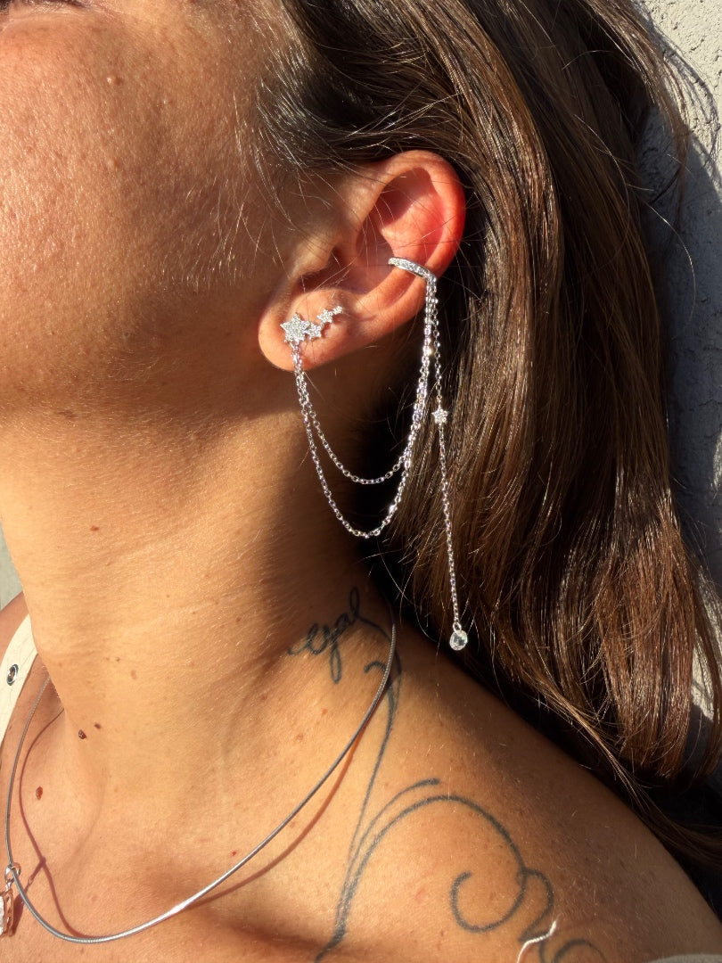 Close-up of a person wearing a silver earring with a chain detail.