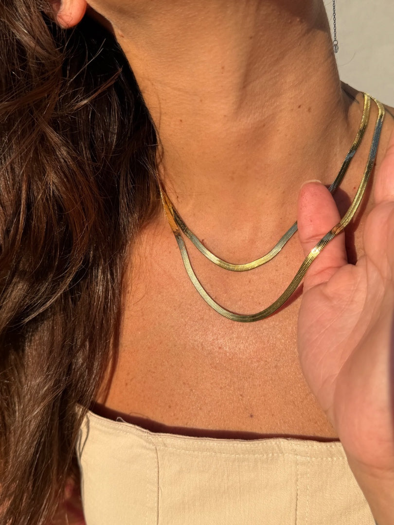 Close-up of a person wearing a gold necklace with a blurred background