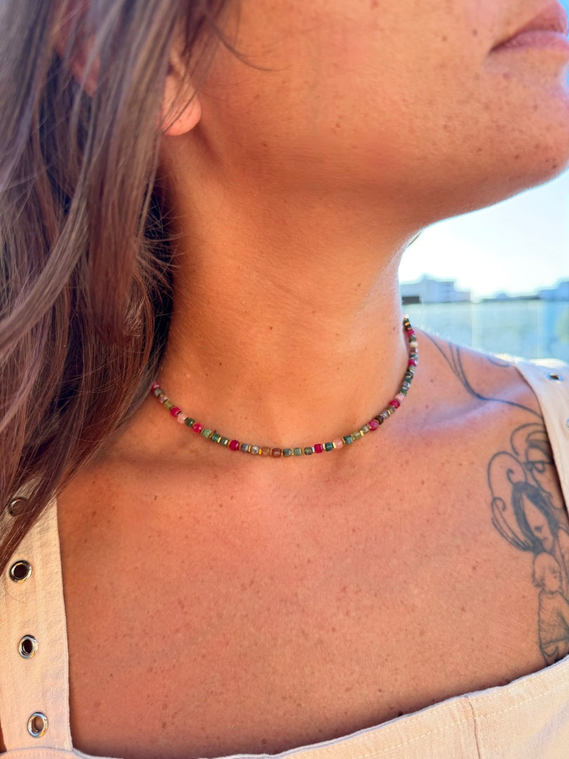 Close-up of a person wearing a colorful beaded necklace with a blurred background