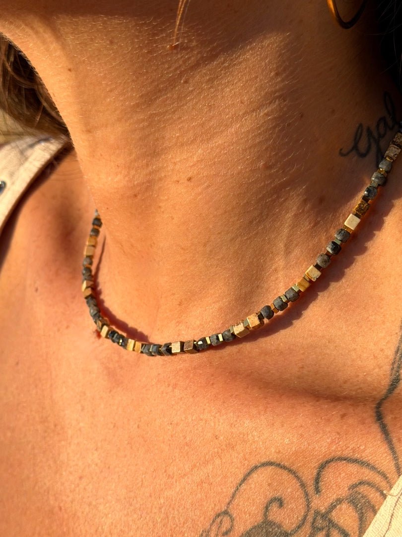 Necklace with small beads on a person's neck with tattoos.