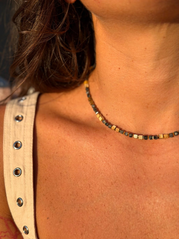 Close-up of a person wearing a beaded necklace with a neutral background