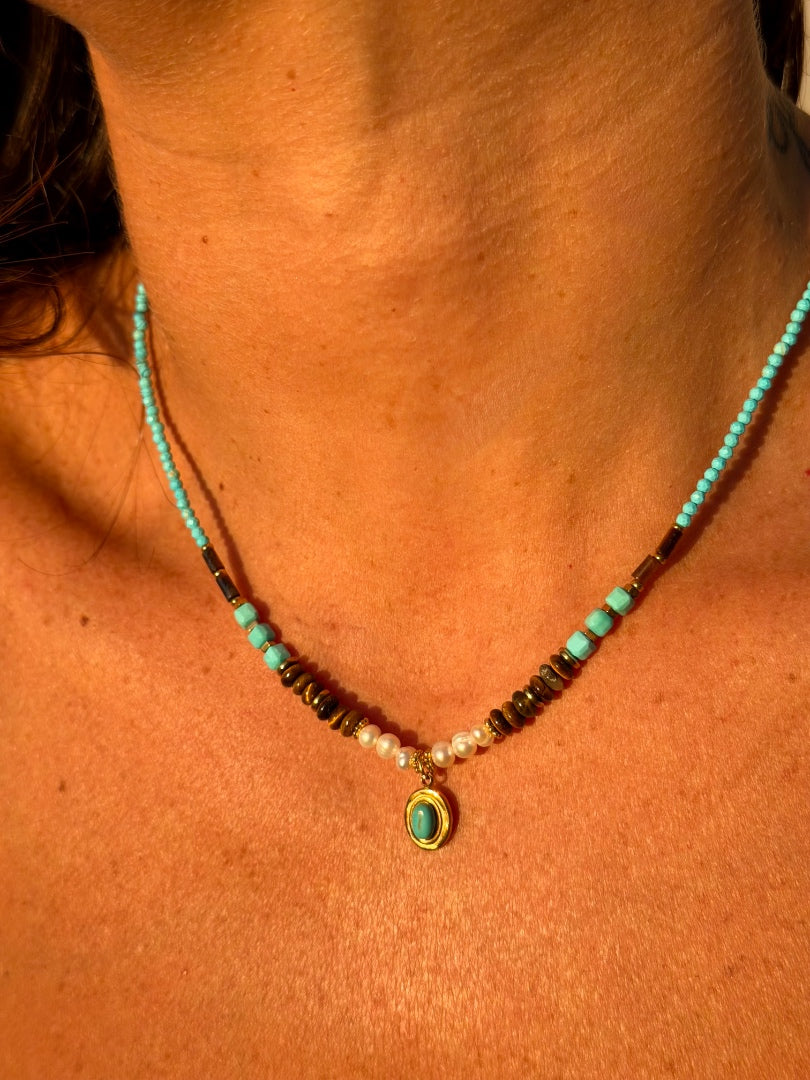 Necklace with turquoise stones and a pendant on a person's neck