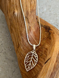 Silver leaf-shaped pendant necklace on a wooden surface
