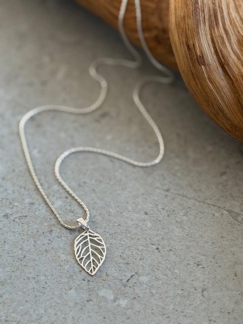 Silver leaf necklace on a textured surface