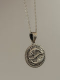 Silver pendant necklace on a plain background