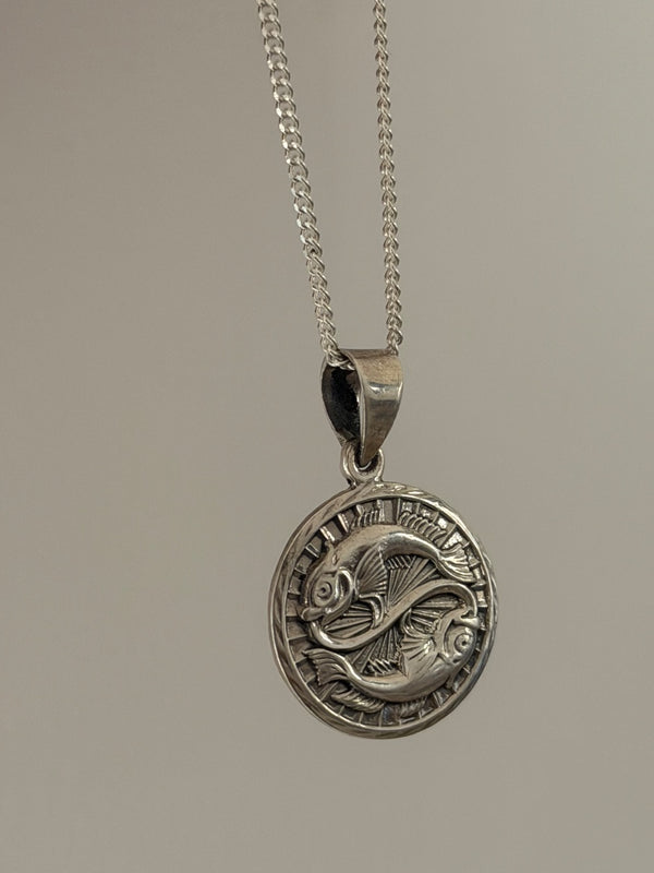Silver pendant necklace on a plain background