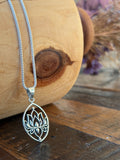 Silver lotus flower pendant necklace on a wooden surface