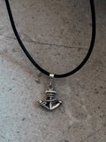 Silver anchor pendant on a black cord against a gray background
