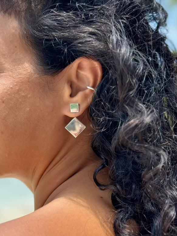Close-up of a person wearing earrings with a blurred natural background