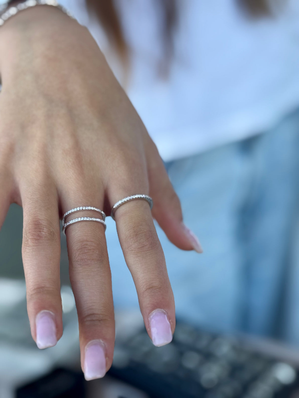 Close-up of a hand wearing two silver rings with a blurred background