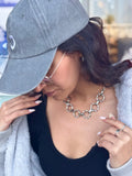 Person wearing a gray cap and light gray sweater with a blurred background