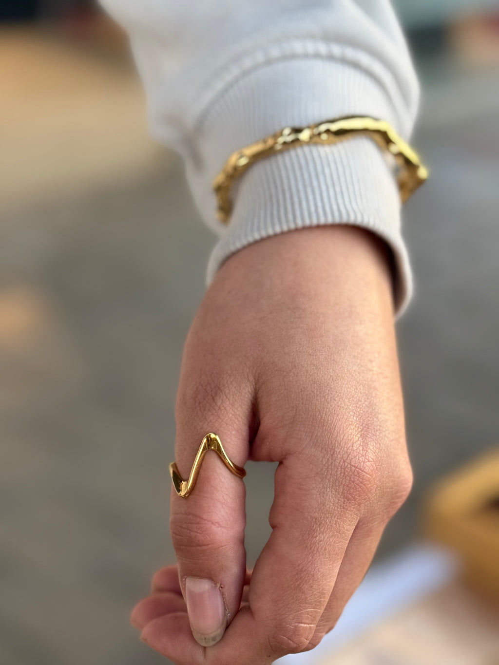 Hand wearing a gold ring with a blurred background