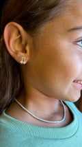 Close-up of a person wearing a pearl necklace and gold earrings.
