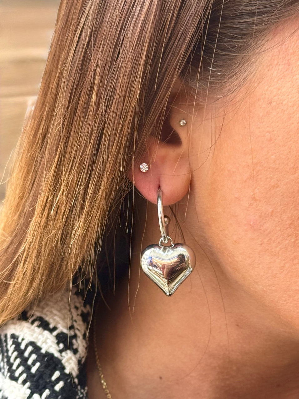 Close-up of a person wearing silver heart-shaped earrings.