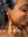 Close-up of a woman wearing silver hoop earrings and a heart-shaped ring.