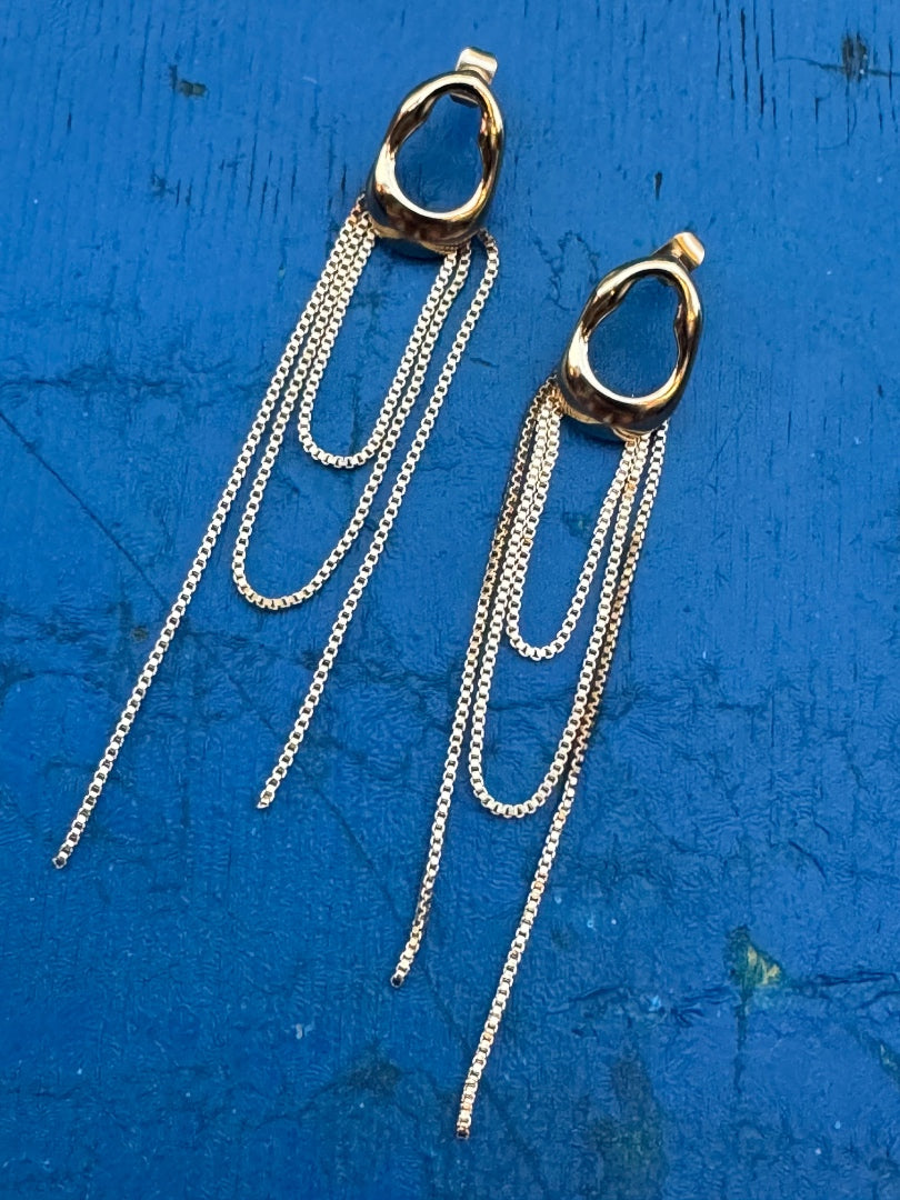 Gold and silver chain earrings on a blue textured background