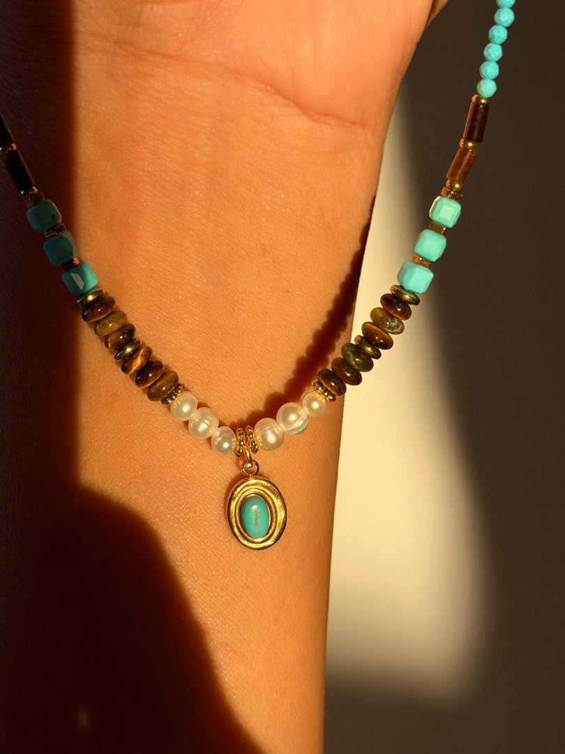 Necklace with turquoise and brown beads on a wrist against a blurred background