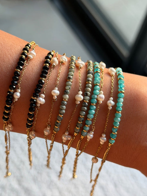 Multiple beaded bracelets on a wrist with a neutral background