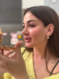 Woman wearing earrings and a necklace, holding a decorative object.