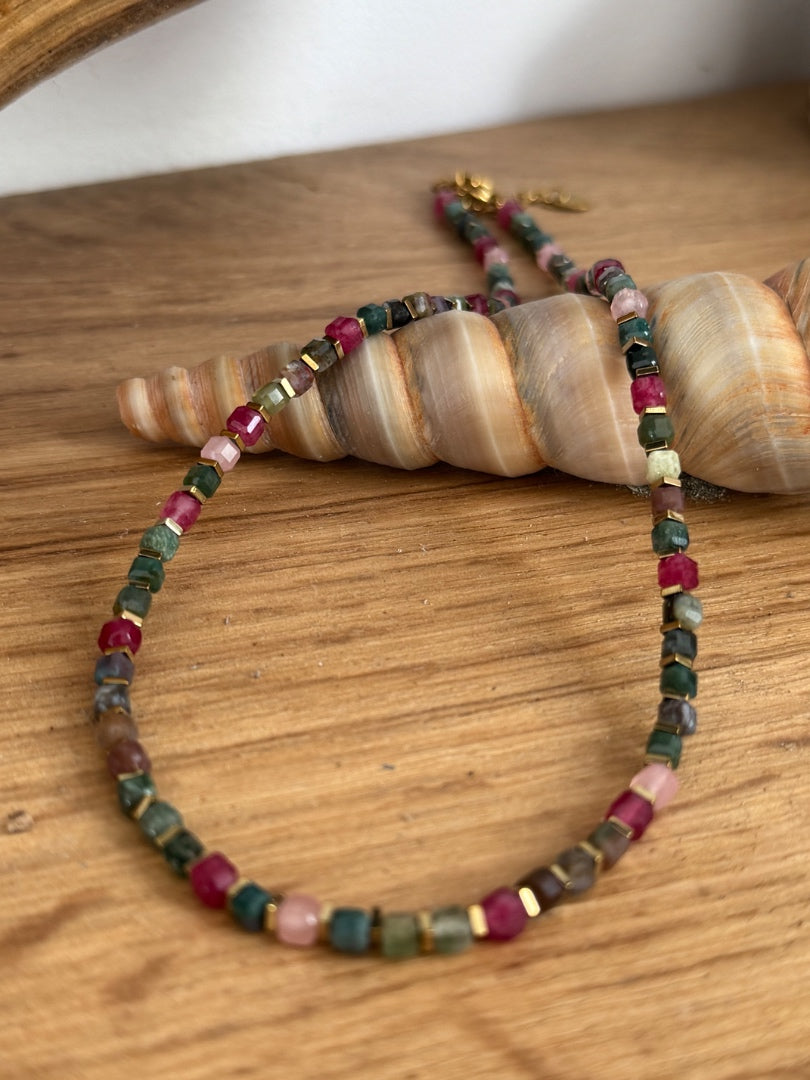 Multicolored beaded bracelet on a wooden surface with a shell in the background