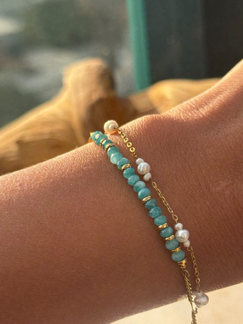 Bracelet with turquoise beads and gold chain on a wrist with a blurred background