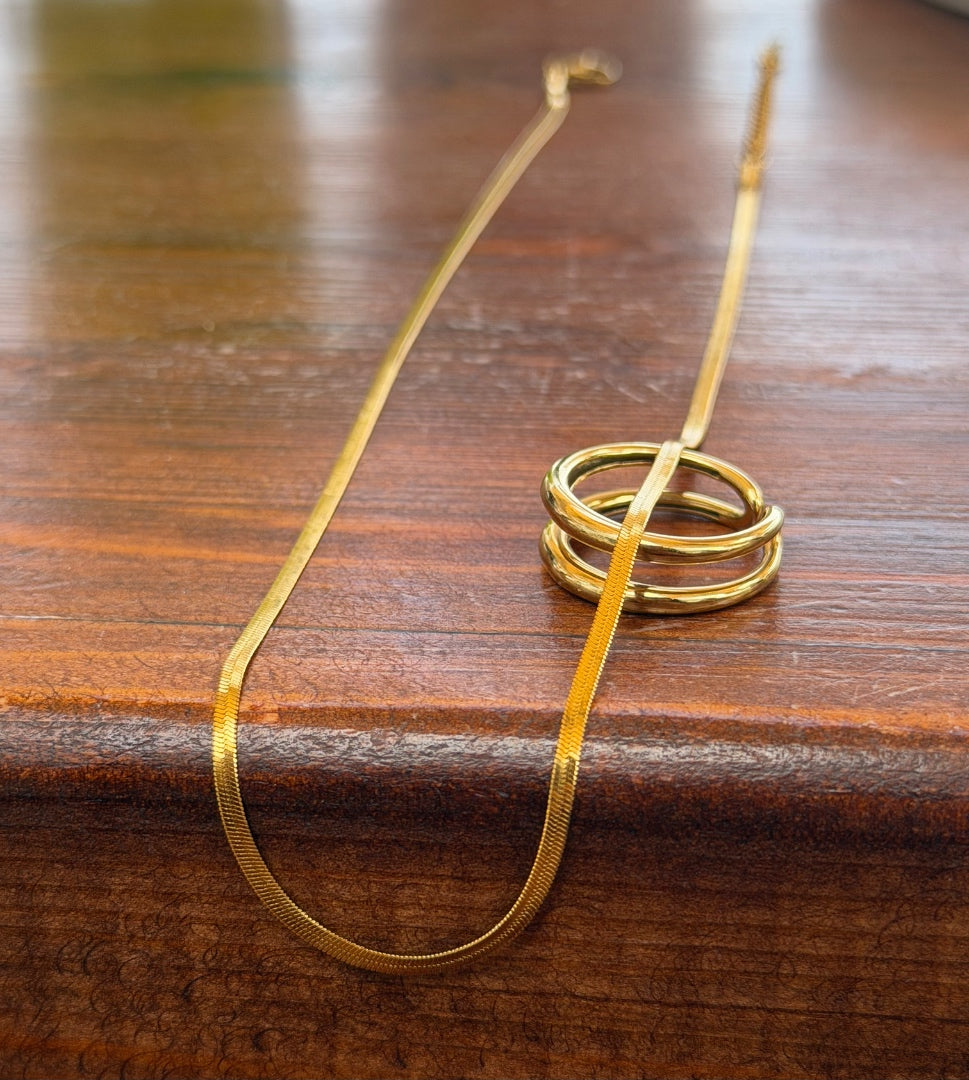 Gold necklace with a spiral design on a wooden surface