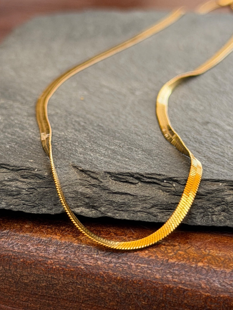 Gold necklace on a dark stone surface