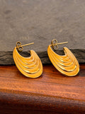 Gold earrings on a wooden surface with a stone background