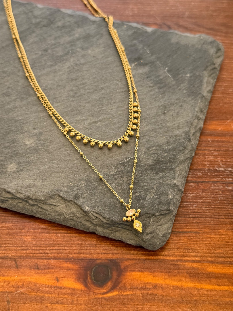 Gold necklace on a dark stone surface with a wooden background