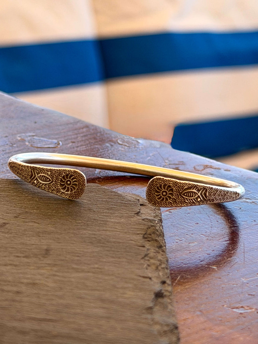 Gold bracelet with intricate designs on a wooden surface