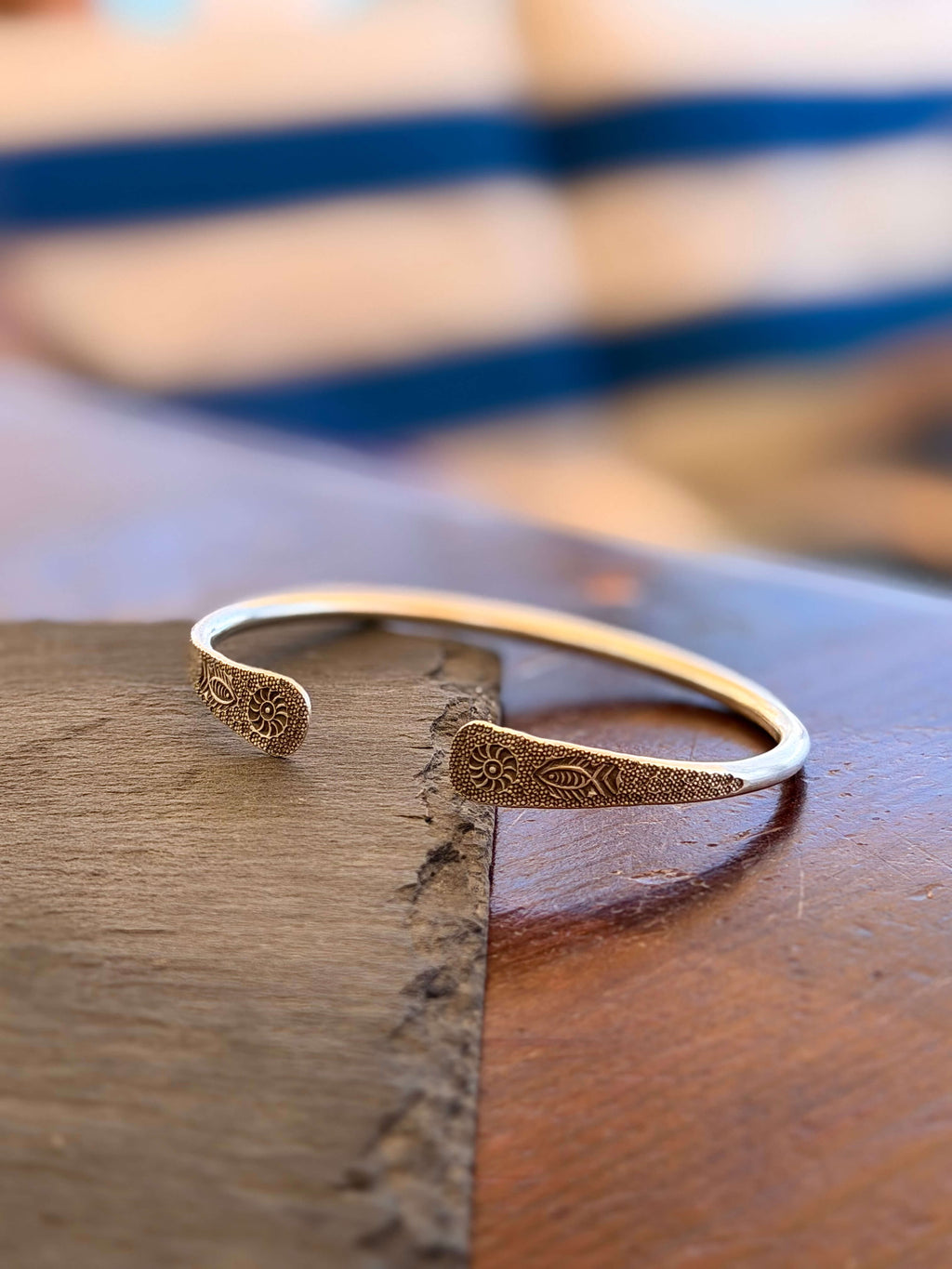 Bronze bracelet on a wooden surface with a blurred background