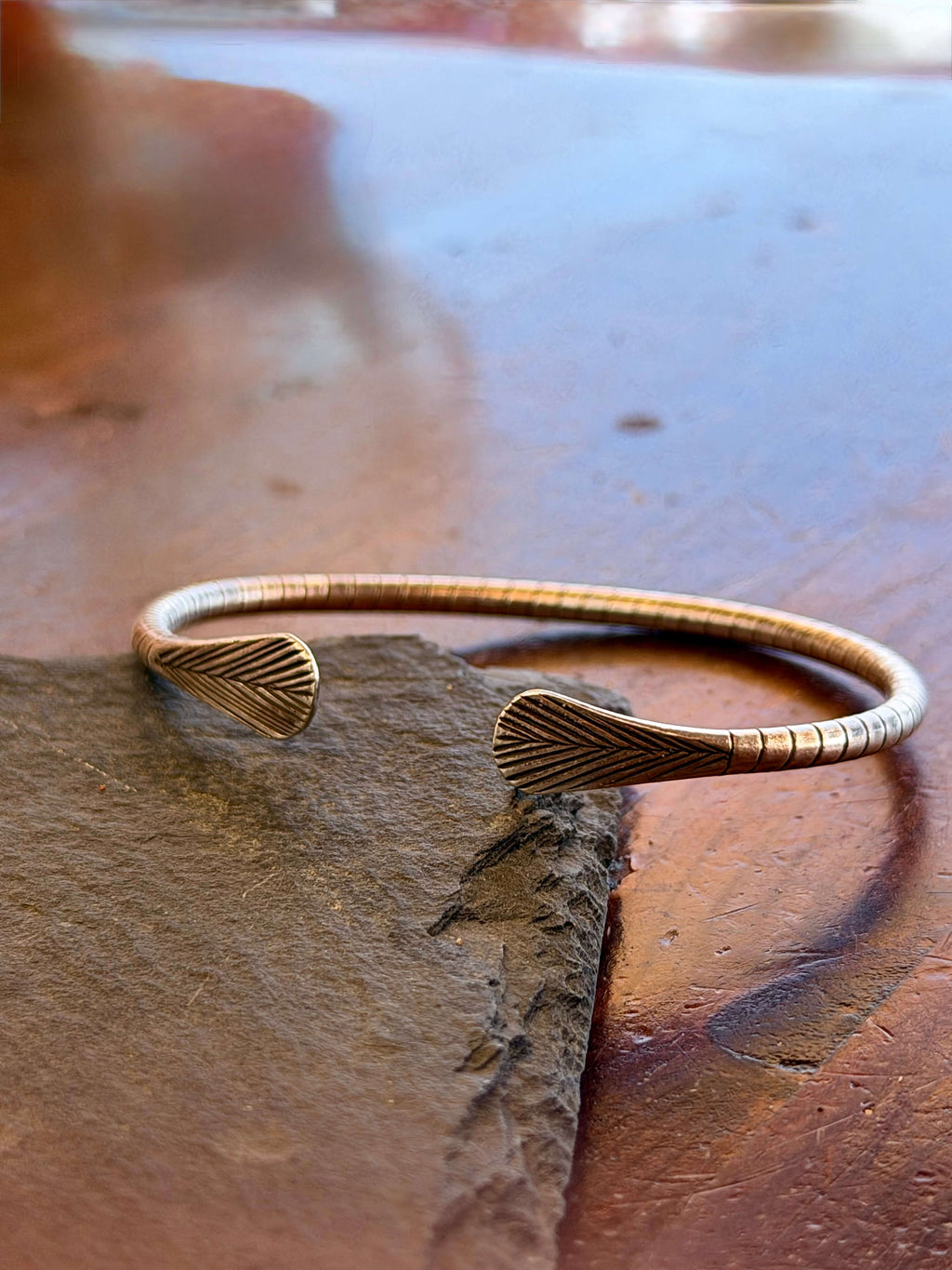 Bronze bracelet on a stone surface with a blurred background