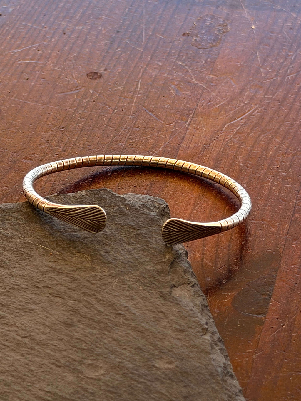 Gold bracelet on a stone surface with a wooden background