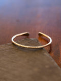 Gold bracelet on a stone surface with a blurred natural background