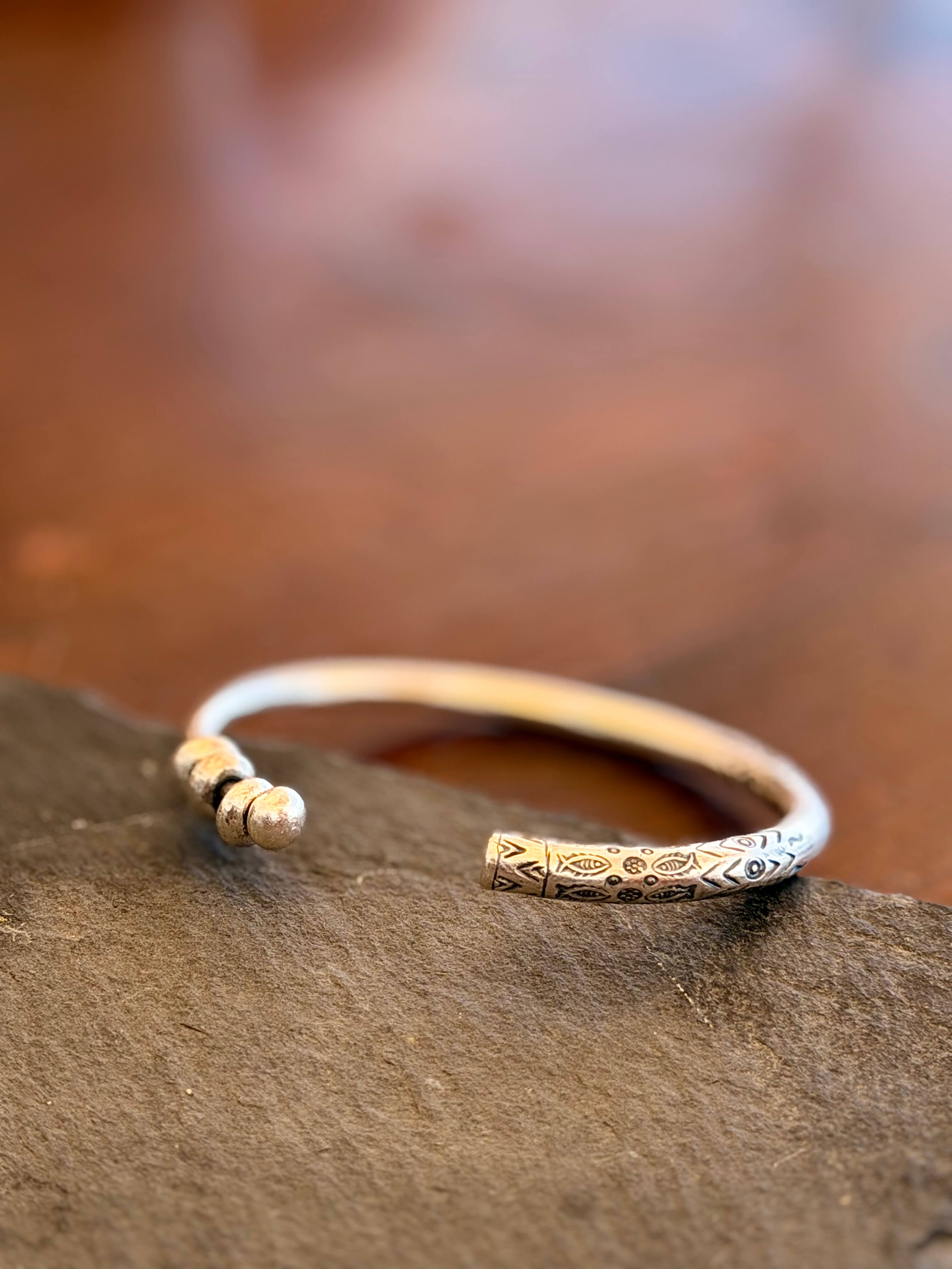 Silver bracelet with intricate designs on a stone surface