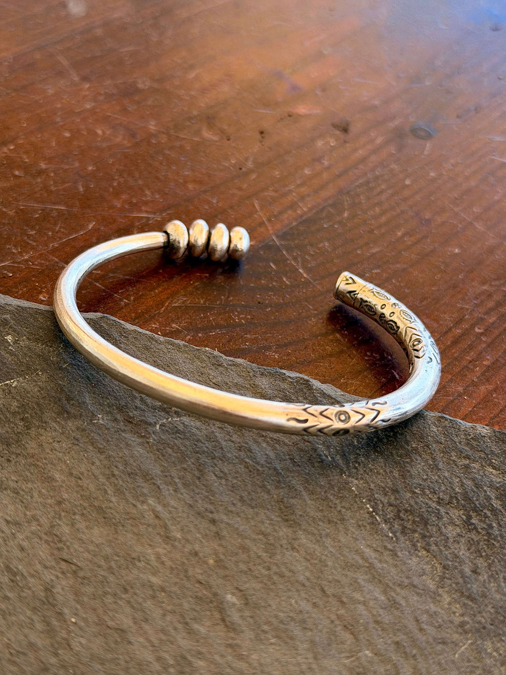 Silver bracelet with intricate designs on a wooden surface