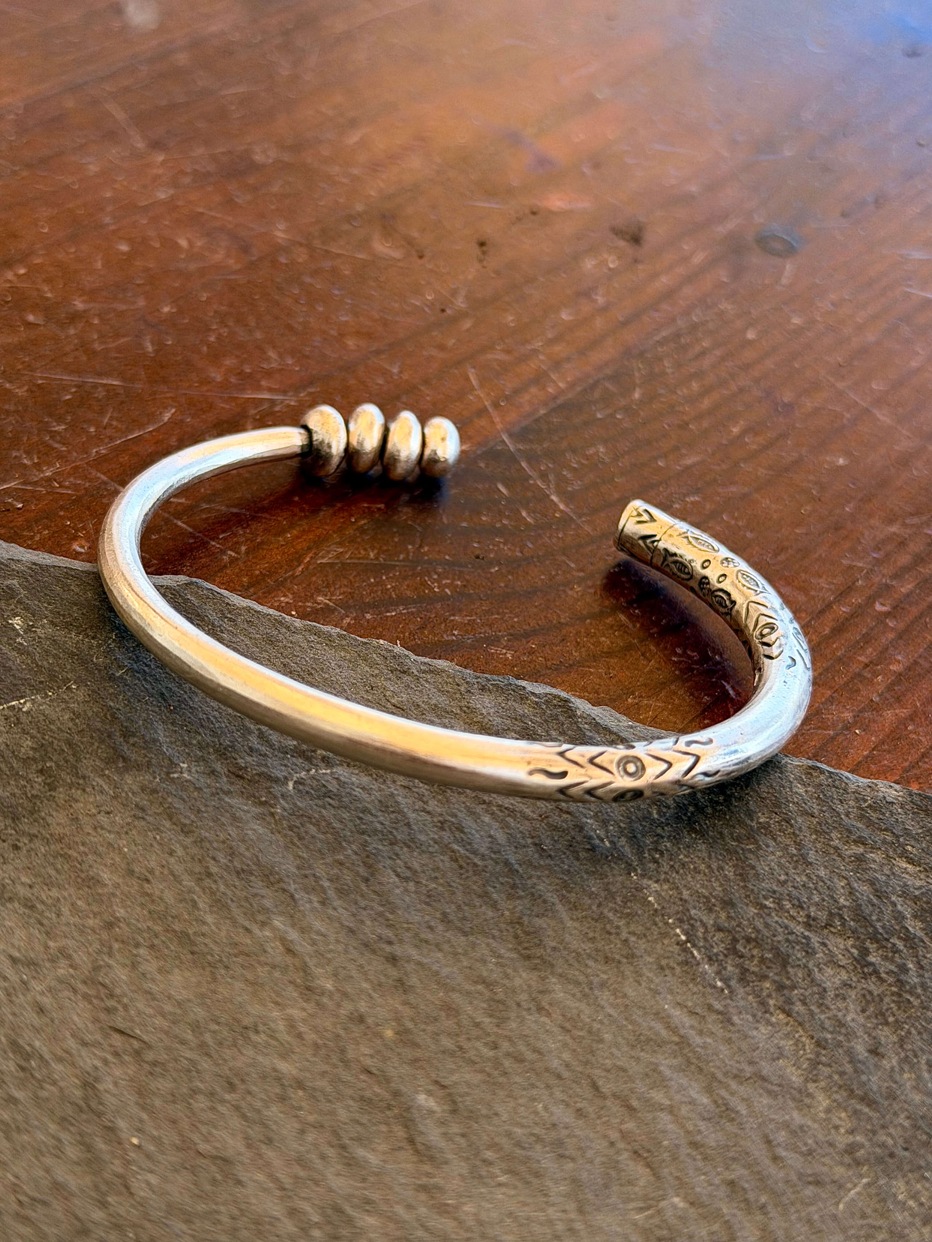 Silver bracelet with intricate designs on a wooden surface