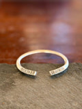 Silver bracelet with intricate designs on a dark stone surface