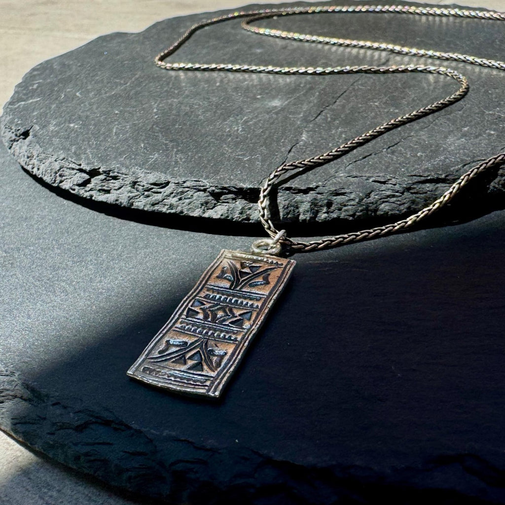 Necklace with a pendant on a dark stone surface