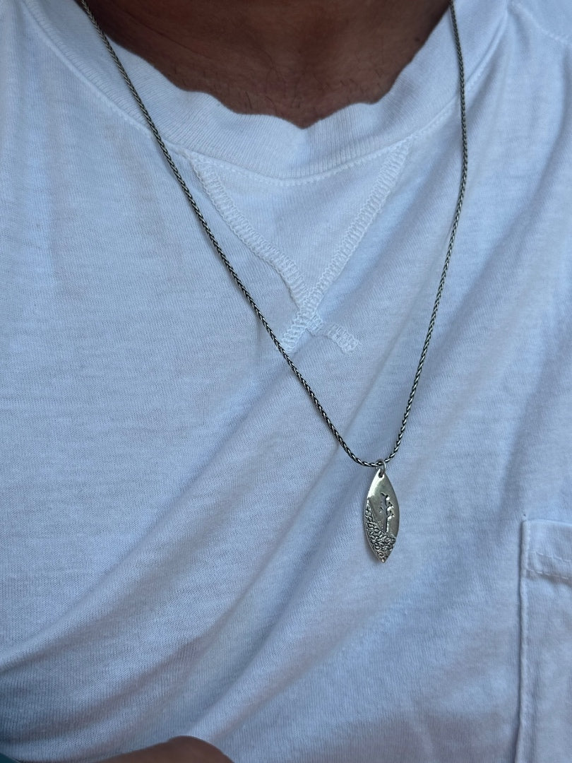 Silver necklace with a pendant on a white shirt