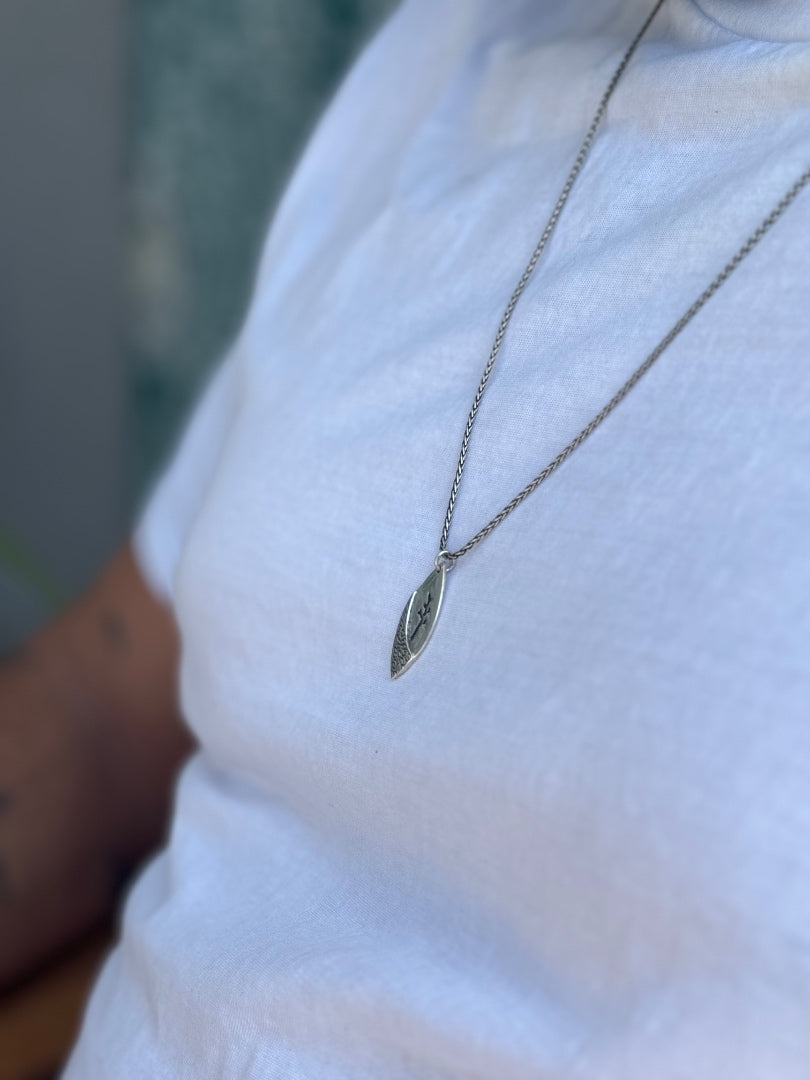 Silver necklace with a pendant on a white shirt